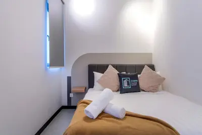 a bed with a white towel laying on it at Neu Suites by COBNB in Kuala Lumpur