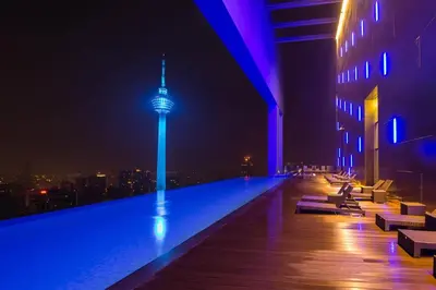 a building with a swimming pool at night with a tower at Maxhome Plus @ The Platinum KLCC in Kuala Lumpur