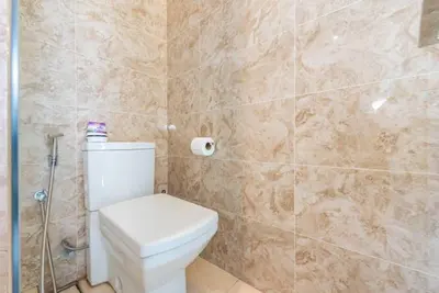 a bathroom with a toilet and a tiled wall at Dorsett Residence Kuala Lumpur 12 in Kuala Lumpur