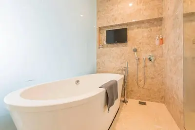 a bathroom with a white tub and a tv on the wall at Dorsett Residence Kuala Lumpur 12 in Kuala Lumpur