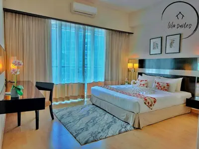 a bedroom with a bed and a desk and a large window at Lila Suites Seri Bukit Ceylon in Kuala Lumpur