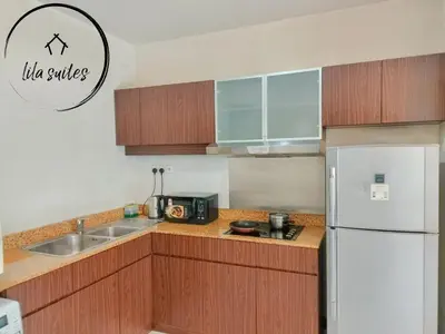 a kitchen with wooden cabinets and a white refrigerator at Lila Suites Seri Bukit Ceylon in Kuala Lumpur