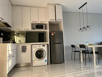 a kitchen with a washing machine and a table with chairs at Summer Suites KLCC By Whollmark in Kuala Lumpur