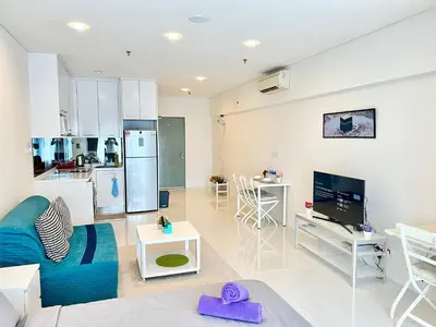 a living room with a blue couch and a kitchen at Summer Suites KLCC By Whollmark in Kuala Lumpur