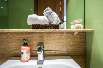 a bathroom sink with a bottle of soap and towels at Calm Sojourn, Sky Suites KLCC in Kuala Lumpur