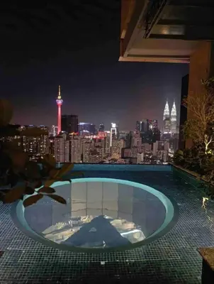 a swimming pool with a view of the city at night at Maxhome Cozy at Lucentia Bukit Bintang City Centre KL in Kuala Lumpur