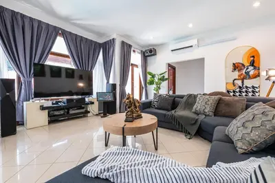 a living room with a couch and a tv at Tropical Bliss Luxe 5BR 30Pax Private Pool Villa KL by Verano in Kuala Lumpur