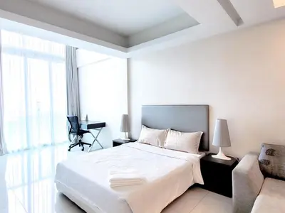 a white bedroom with a bed and a chair at Damas Residence Kuala Lumpur in Kuala Lumpur