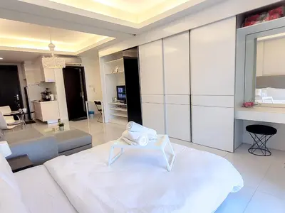 a bedroom with a white bed and a living room at Damas Residence Kuala Lumpur in Kuala Lumpur