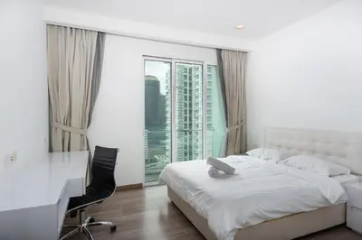 a bedroom with a bed and a desk and a window at MyRehat Suites Bukit Ceylon in Kuala Lumpur
