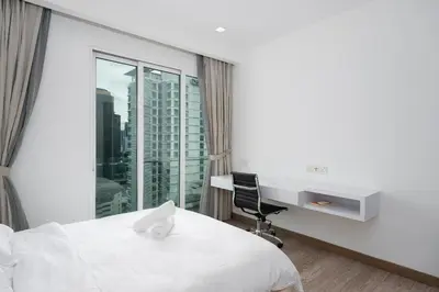 a bedroom with a bed and a desk and a window at MyRehat Suites Bukit Ceylon in Kuala Lumpur
