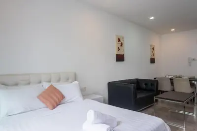 a bedroom with a white bed and a black chair at MyRehat Suites Bukit Ceylon in Kuala Lumpur