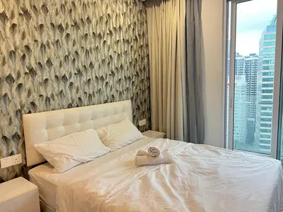 a bedroom with a white bed with a large window at MyRehat Suites Bukit Ceylon in Kuala Lumpur
