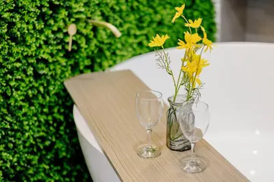 a table with two glasses and a vase with yellow flowers at The Pano Residence Jalan Ipoh Insta-worthy Bath Tub Studio \u6d74\u7f38MRT in Kuala Lumpur