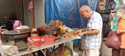 a man preparing food on a table in a market at Plaza Berjaya Apt Bukit Bintang with Pool Table in Kuala Lumpur