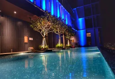 a swimming pool in a building with trees and blue lights at Expressionz Leisure Suites KLCC in Kuala Lumpur