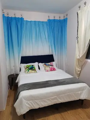 a bedroom with a large bed with blue curtains at Ampang Hilir Lake View in Kuala Lumpur