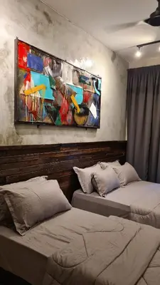 two beds in a room with a painting on the wall at Bricks & Beds Suite @ Legasi Kg Bahru in Kuala Lumpur