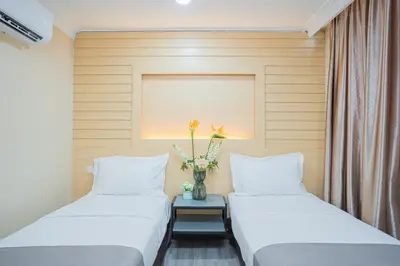 two beds in a room with a vase of flowers at Hotel 28 Titiwangsa in Kuala Lumpur