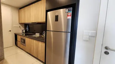 a stainless steel refrigerator in a kitchen with wooden cabinets at Balcony Unit @ Robertson Residence 18f in Kuala Lumpur