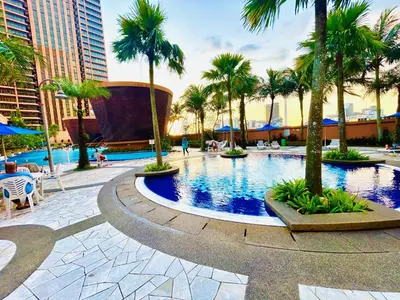 a large swimming pool with palm trees and buildings at APARTMENT by Times Square KL in Kuala Lumpur