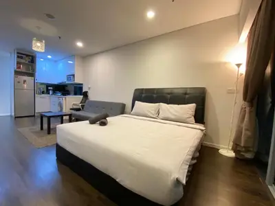a bedroom with a large bed and a kitchen at Summer Suites Apartment 7min walk to KLCC by GRIHOZ in Kuala Lumpur