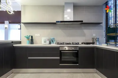 a kitchen with black cabinets and a stove top oven at KL Townhouse Villa by LilyandLoft in Kuala Lumpur