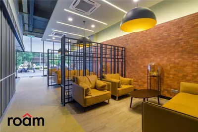 a lobby with yellow chairs and a brick wall at Neu Suites Residence, Embassy Row in Kuala Lumpur