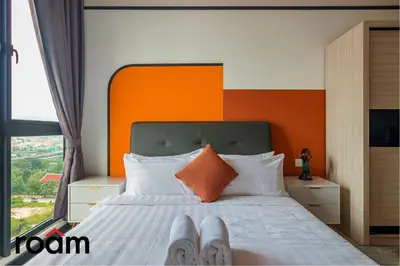a bedroom with a bed with an orange wall at Neu Suites Residence, Embassy Row in Kuala Lumpur