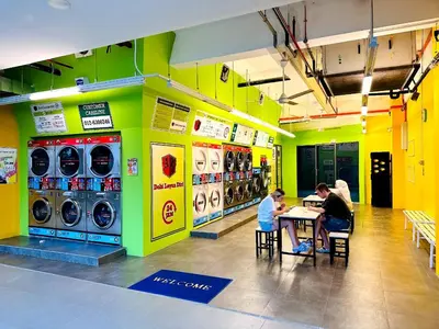 a group of people sitting at a table in a laundry room at The Colony Stay Well studio with KL View in Kuala Lumpur