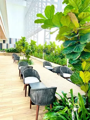 a row of tables and chairs in a building with plants at The Colony Stay Well studio with KL View in Kuala Lumpur