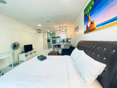 a bedroom with a large white bed and a living room at Mercu Summer Suites KLCC by GRIHOZ Homestay in Kuala Lumpur