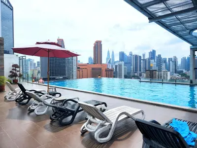 a pool with chairs and an umbrella on top of a building at Infini Suites@ D'Majestic Place Kuala Lumpur in Kuala Lumpur