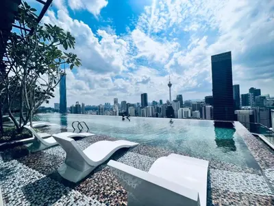 a swimming pool with chairs and a city skyline at Axon Serviced Suites Kuala Lumpur in Kuala Lumpur