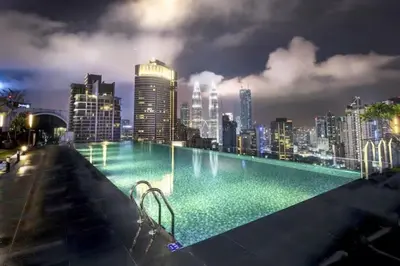 a swimming pool with a city skyline at night at Maxhome Cozy at Dorsett Bukit Bintang in Kuala Lumpur