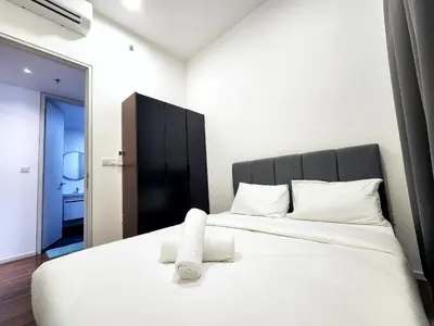 a bedroom with a white bed with a black headboard at Infini Suites@ UNA Residences, Sunway Velocity KL in Kuala Lumpur