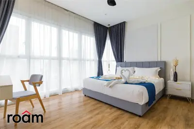 a bedroom with a bed and a chair and windows at Quill Residences KLCC, Five Senses in Kuala Lumpur