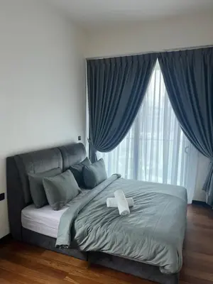 a bed with a white towel on it in front of a window at Opus Residences 2 Bedroom Apartment in Kuala Lumpur