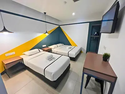 a room with two beds and a desk and a tv at Seeds Hotel Chow Kit in Kuala Lumpur