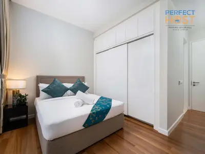 a bedroom with a bed with white sheets and blue pillows at Pavilion Ceylon Hill Suites, Bukit Bintang by Perfect Host in Kuala Lumpur