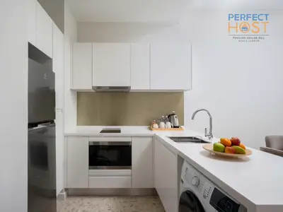 a kitchen with white cabinets and a bowl of fruit on the counter at Pavilion Ceylon Hill Suites, Bukit Bintang by Perfect Host in Kuala Lumpur