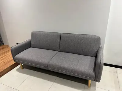 a gray couch sitting in a room next to a wall at Opus Residences 1 Bedroom Apartment in Kuala Lumpur