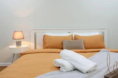 a bedroom with a large bed with orange sheets and pillows at Sky Suites KLCC By Calm Sojourn in Kuala Lumpur