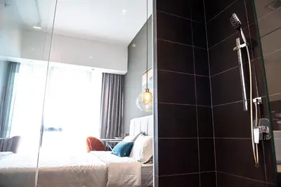 a bathroom with a glass shower with two beds at Stay @ NOVO Ampang in Kuala Lumpur