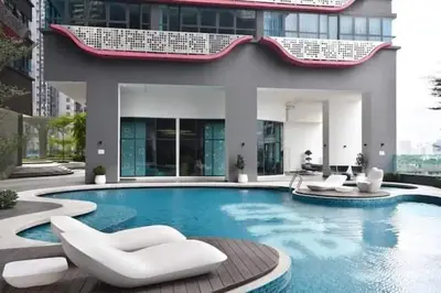 a swimming pool with two white chairs and a building at Arte plus by sweet home 2BR in Kuala Lumpur
