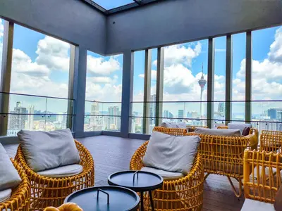 a balcony with wicker chairs and tables and windows at The Axon Residence - Bukit Bintang Kuala Lumpur in Kuala Lumpur
