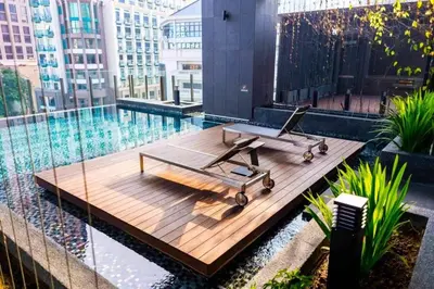 a bench on a wooden platform next to a swimming pool at Klcc studio with a rooftop garden playground in Kuala Lumpur