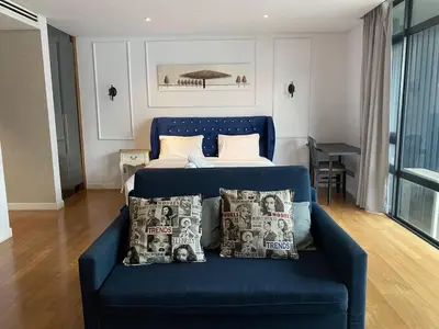 a blue couch in a room with a bed at Klcc studio with a rooftop garden playground in Kuala Lumpur