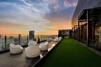 a balcony with white chairs on the roof of a building at Klcc studio with a rooftop garden playground in Kuala Lumpur