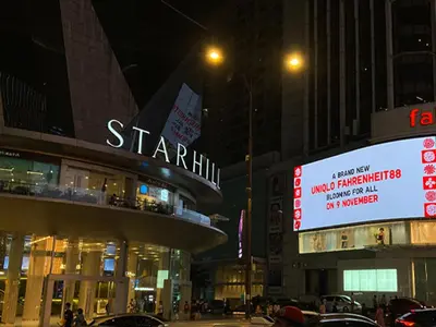 a city street at night with a sign for a store at KAĨTE Homestay at Fahrenheit88 Bukit Bintang, Opposite Pavilion KL in Kuala Lumpur